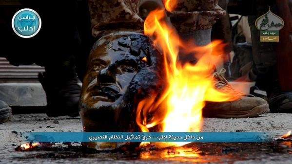 مسلحو المعارضة السورية يحرقون تمثالا لحافظ الأسد بعد السيطرة الكاملة على إدلب 